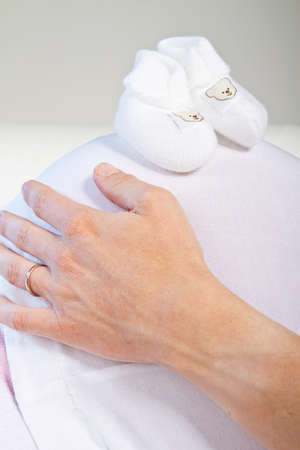 Young fresh pregnant woman with baby toys. Isolated over white background.