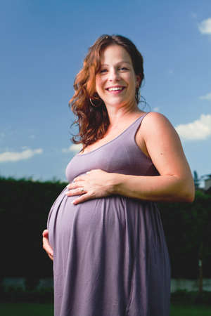 Young pregnant woman stand in grass. Beautiful and happy model.の写真素材