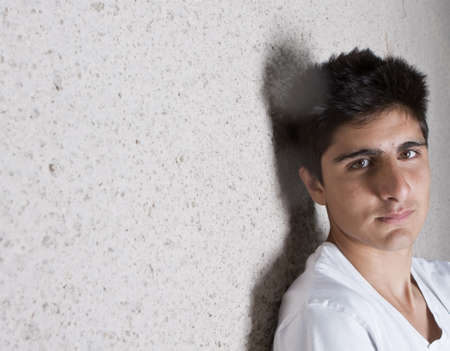 Young teenage boy leaning against a wall in anurban setting. の写真素材