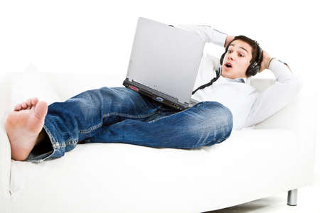 Young man relaxing on the couch listening to music over white background.