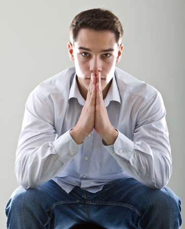 Young cute, handsome and thoughtful man with his hands