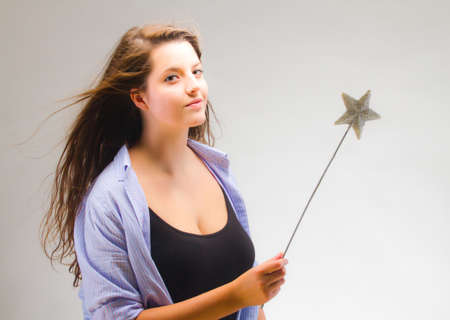 Young woman with a magic wand over grey background.の写真素材
