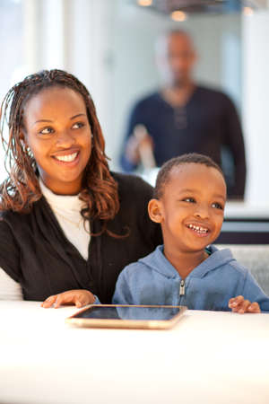 Kitchen setting with young black family playing with a tablet pc.