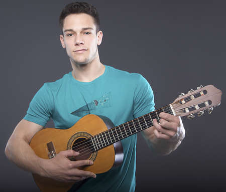 Young Man Playing Guitar Over Gray Backgroundの写真素材
