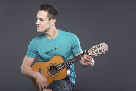 Young Man Playing Guitar Over Gray Backgroundの写真素材