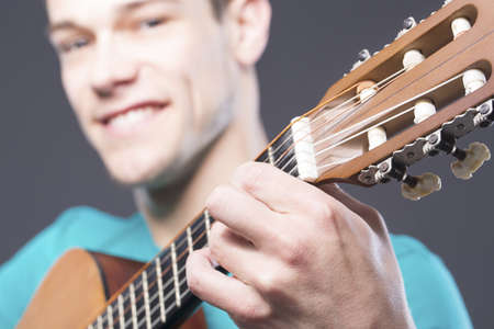 Close-up Of Happy Young Man With Guitar  Over Gray Backgroundの写真素材