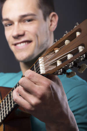 Close-up Of Happy Young Man With Guitar Over Gray Backgroundの写真素材