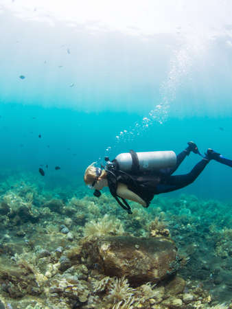 Female Scuba diver hovering over a coral reef at Tulamben, Bali Indonesiaの写真素材