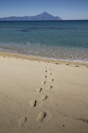 footprints in the sand, in the distance is Mount Athos