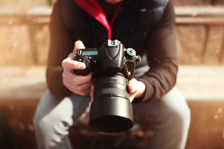 Man holding dslr camera in hands. Digital photography background.