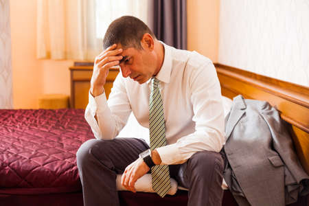 Worried businessman sitting in hotel room and thinkingの写真素材