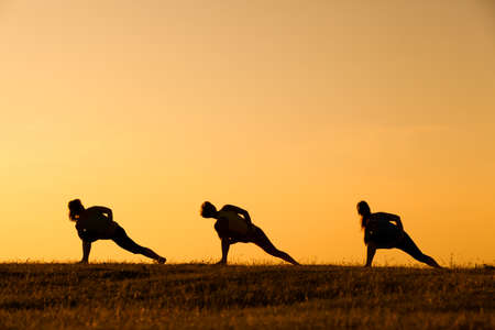 Silhouettes of girls practicing yoga in sunset