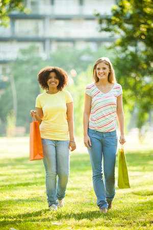 Two happy women in park after shoppingの写真素材