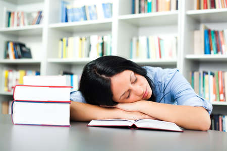 Tired student sleeping in libraryの写真素材