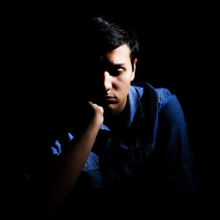 Portrait of a depressed man, black backgroundの写真素材