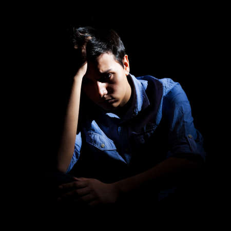 Portrait of a depressed man, black backgroundの写真素材
