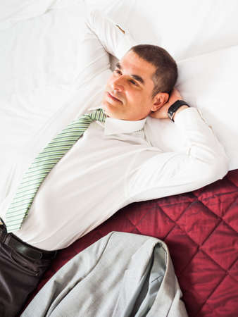 Businessman is resting on a bed and thinkingの写真素材