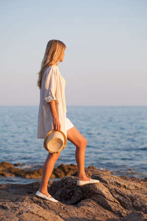 Woman standing on rock and looking at seaの写真素材