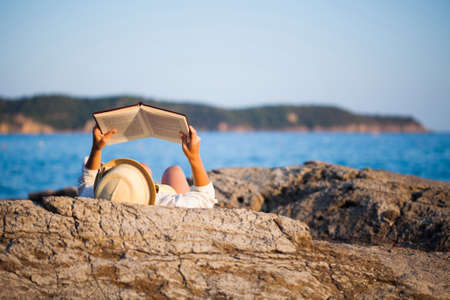 Woman reading a book on the seashoreの写真素材