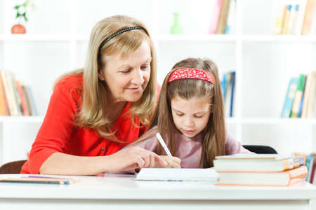 Grandmother helping her granddaughter to learn to writeの写真素材