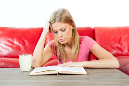 Young woman reading book, having cup of coffeeの写真素材