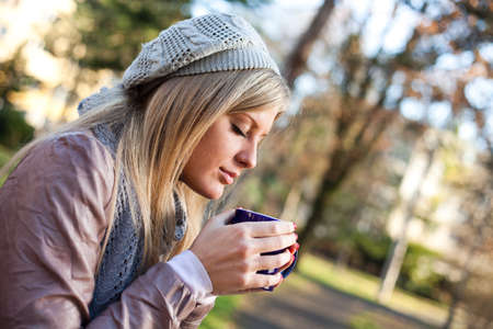 Young woman drinking tea in parkの写真素材
