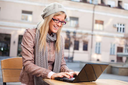 Happy girl using laptop in a sidewalk cafeの写真素材
