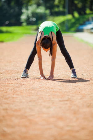 Young woman stretching body, warming up for joggingの写真素材