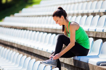 Young woman tying a shoelace before joggingの写真素材