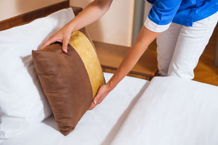 Maid making bed in hotel roomの写真素材