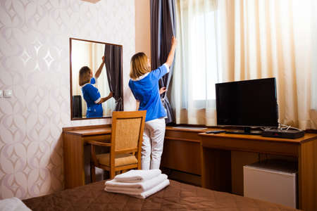 Hotel maid fixing the curtainの写真素材