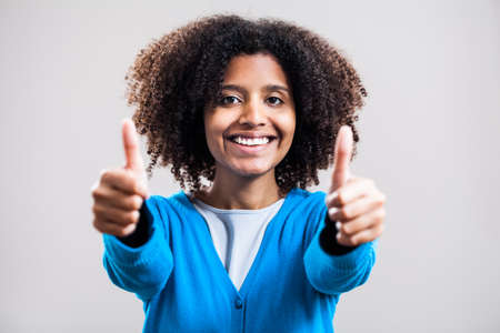 Young woman smiling and showing thumb-upの写真素材
