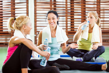 Happy women relaxing and talking after fitness trainingの写真素材