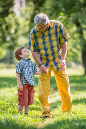 Grandfather and grandson talking in parkの写真素材