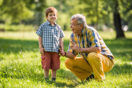 Grandfather and grandson talking in parkの写真素材