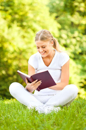 Young woman reading book in parkの写真素材