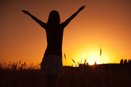Silhouette of woman enjoying sunsetの写真素材