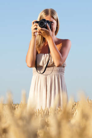 Young woman photographing in wheat fieldの写真素材