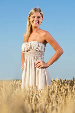 Portrait of a beautiful girl standing in wheat fieldの写真素材