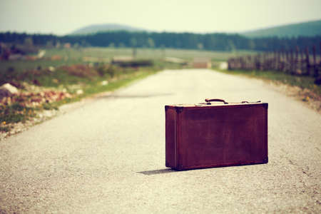 Vintage suitcase on the road intentionally toned.の写真素材