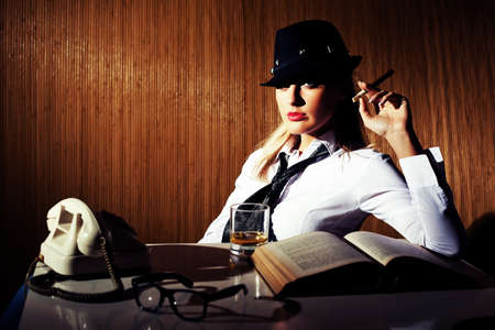 Retro styled businesswoman smoking cigar and drinking whiskey intentionally toned.