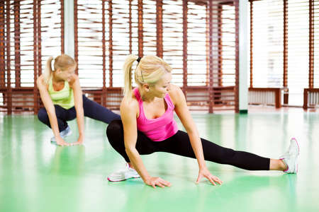 Girls exercising in gym stretching their legsの写真素材