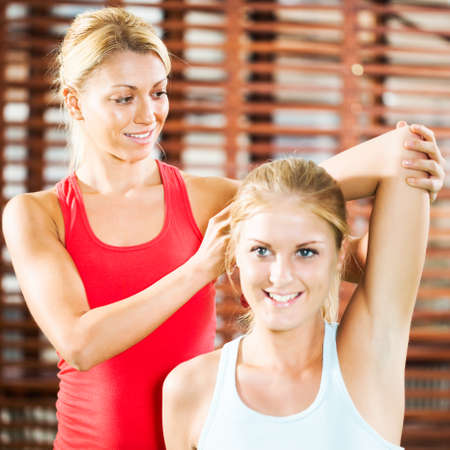 Woman exercising in gym with fitness instructorの写真素材