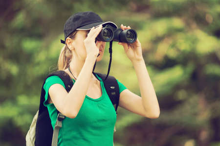 Hiker looking through binoculars in forest intentionally tonedの写真素材