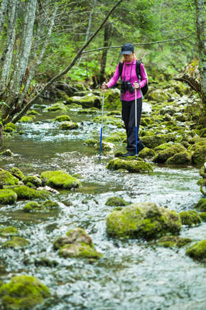 Hiker in forest crossing the streamの写真素材