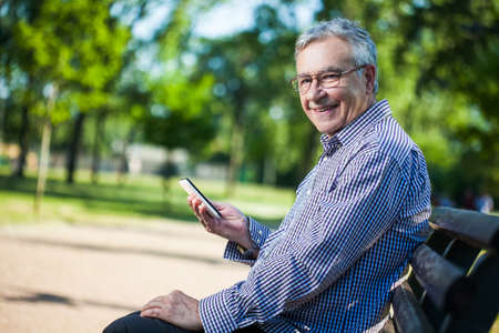 Senior man using digital tablet in parkの写真素材