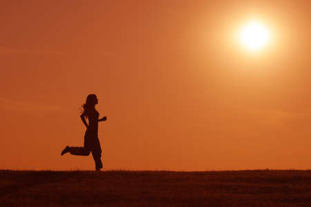 Silhouette of girl jogging in the sunsetの写真素材