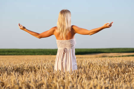 Young woman enjoying sun in wheat fieldの写真素材