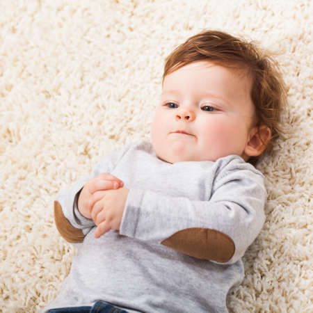 Cute baby boy lying on floorの写真素材