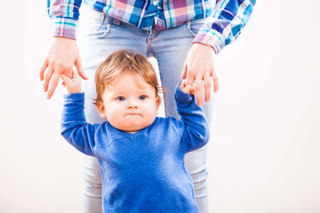 Little boy learning to walk with help from his motherの写真素材